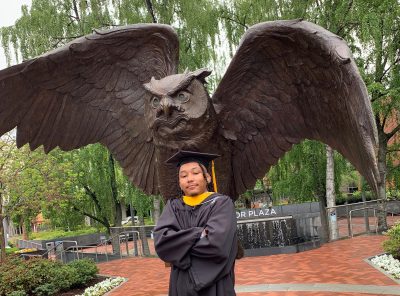 Jamar Root standing in front of an owl statue on Temple University campus