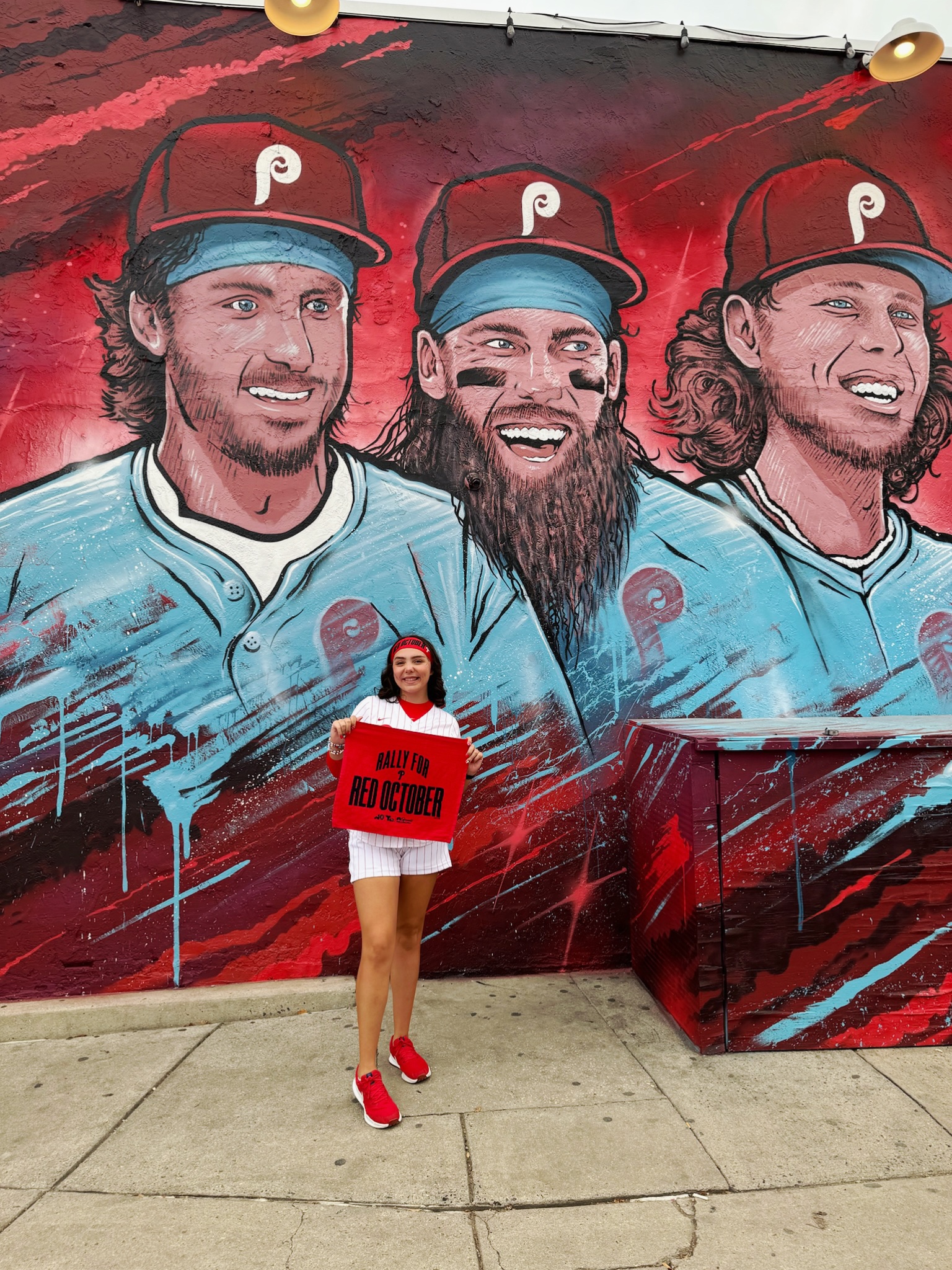 Megan Gochenauer takes her Phillies spirit with her to the Phillies mural at Garage on Girard Avenue in Philadelphia.